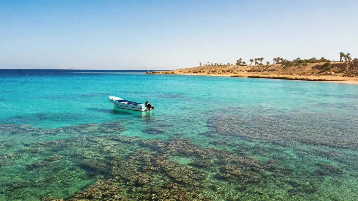A small boat over clear turquoise water and coral reef off the Red Sea coast
