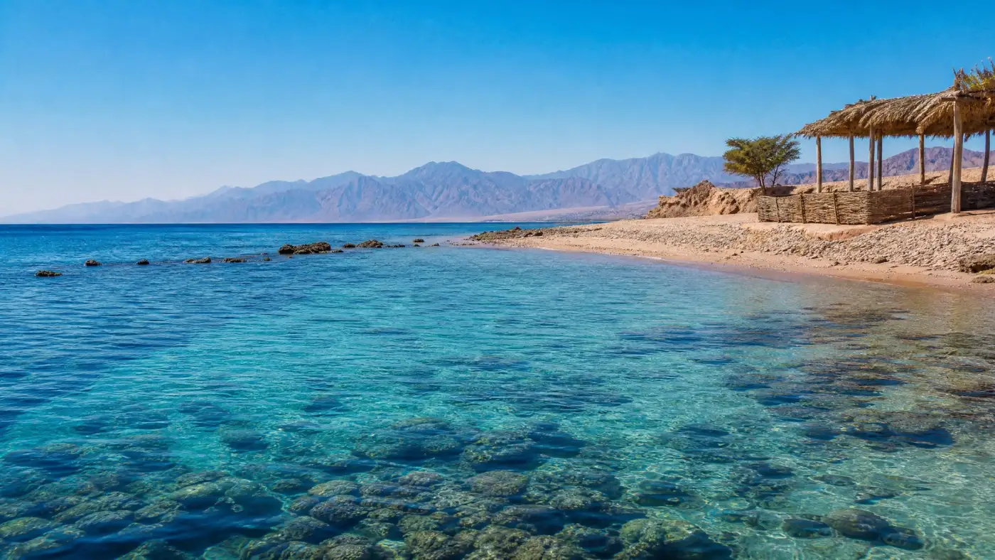 A sandy beach and clear reef water beneath the mountains of South Sinai